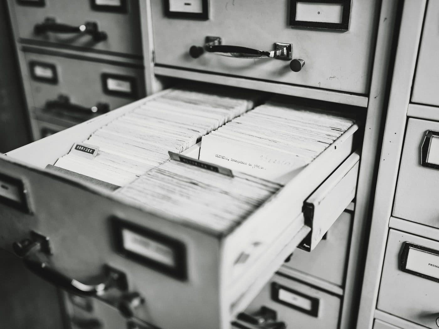 An open drawer of index cards in a grey filing cabinet.